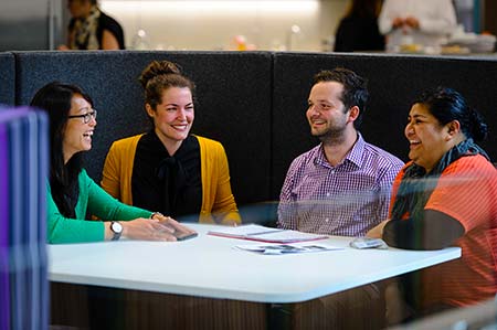 Parents sitting on sofa. Mum is holding her baby boy and interacting with him.
